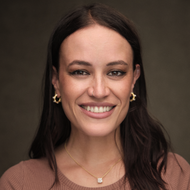 Maeva Cifuentes - Headshot of a smiling woman with dark hair, wearing gold jewelry.