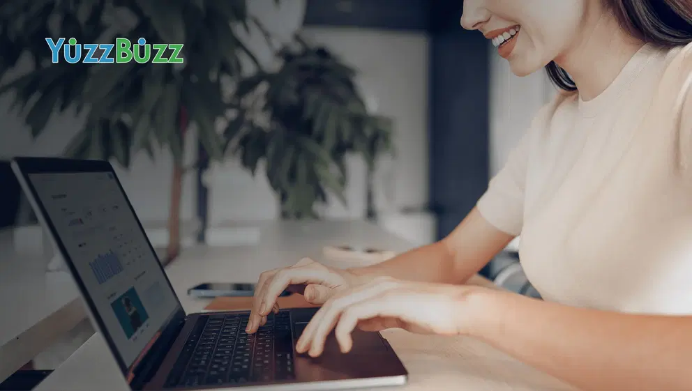 Yuzz Buzz - Woman smiling while using a laptop.